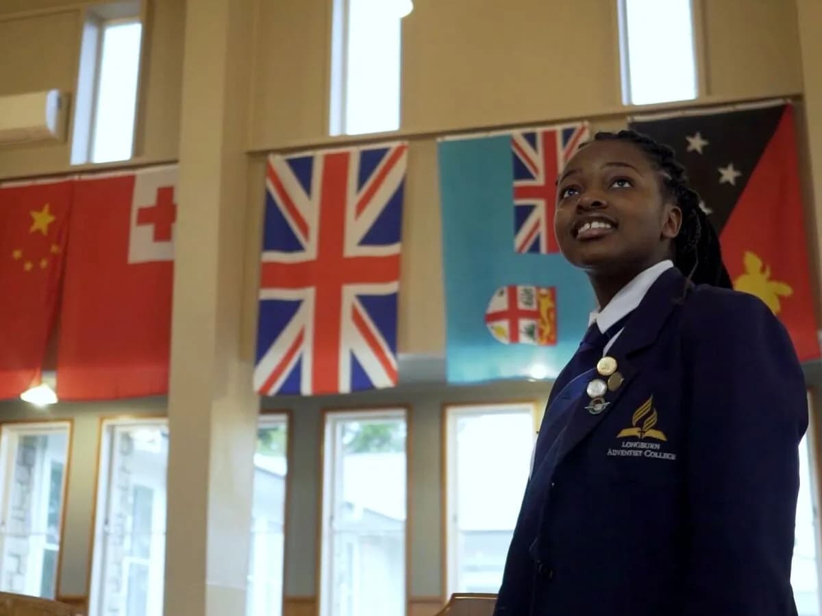 Student speaking in the school hall beneath international flags