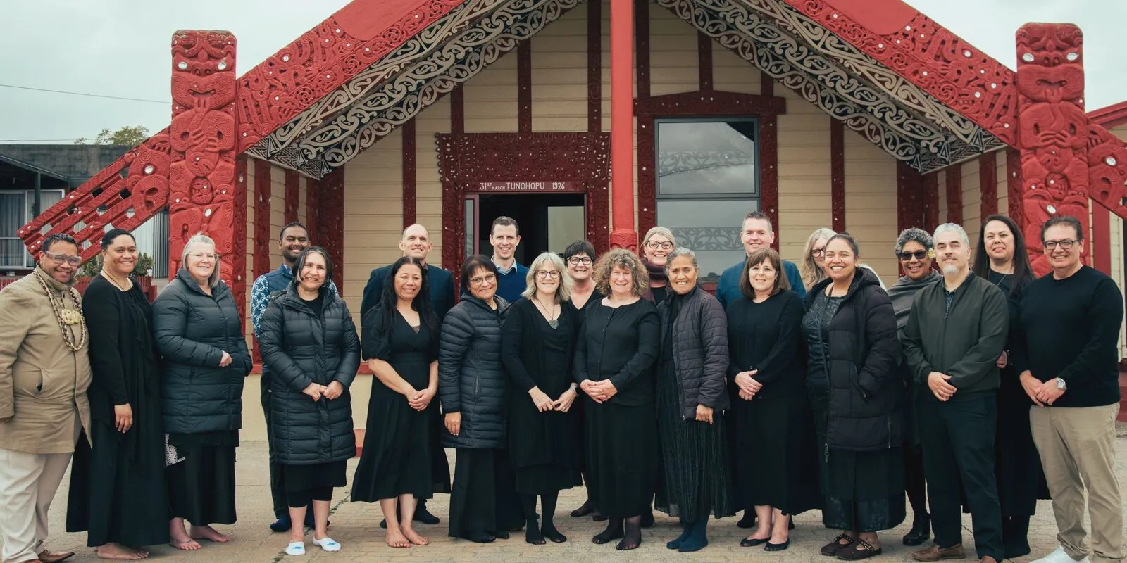 School principals standing together in front of a carved wharenui at the marae