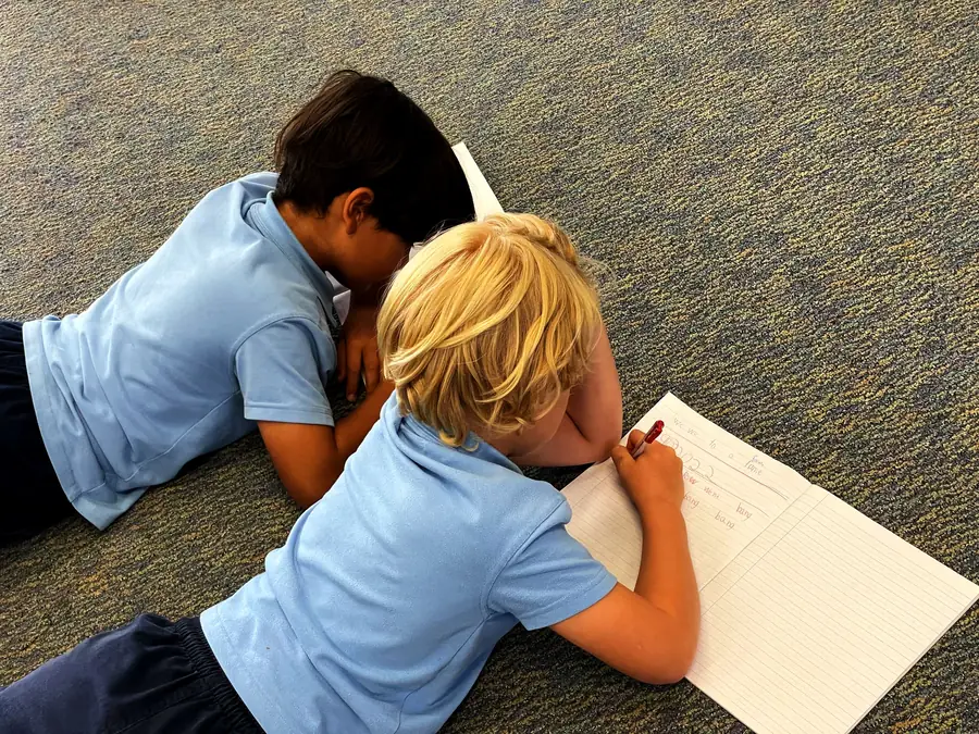 Two primary students reading together on the classroom floor