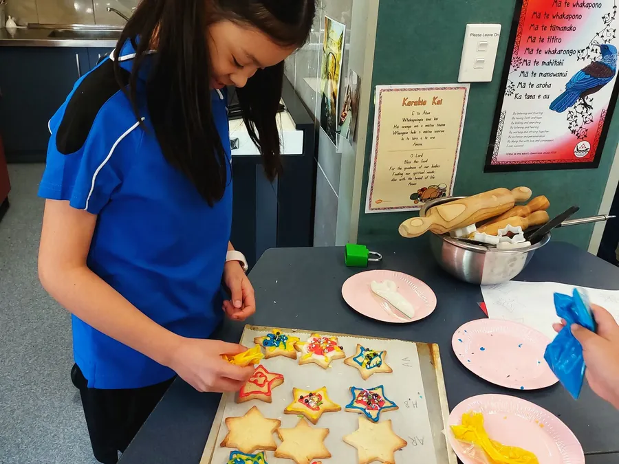 Primary student decorating star biscuits in a cooking class
